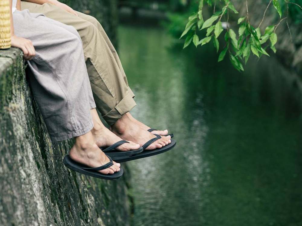 水路に足を垂らす二人とサンダル
